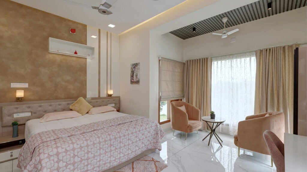 A luxurious bedroom featuring a tufted headboard, blush armchairs, and golden accent walls — blending comfort with contemporary elegance under warm ambient lighting.